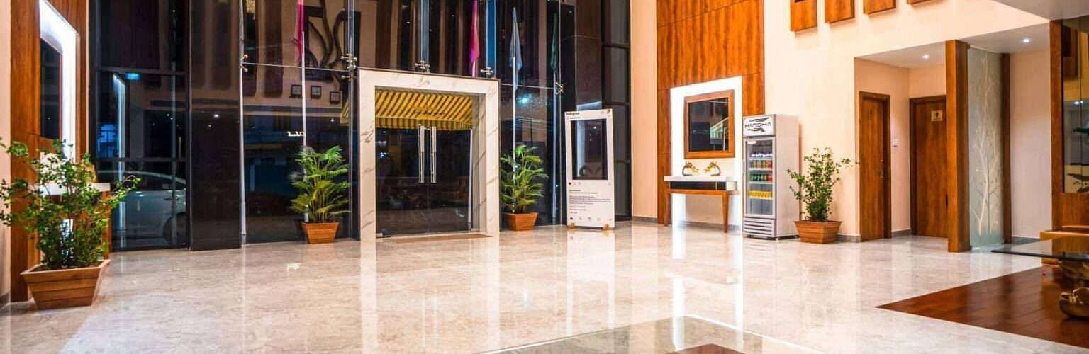 The bright and airy lobby of Mansha Palace features large windows, wooden paneling, and a fountain.