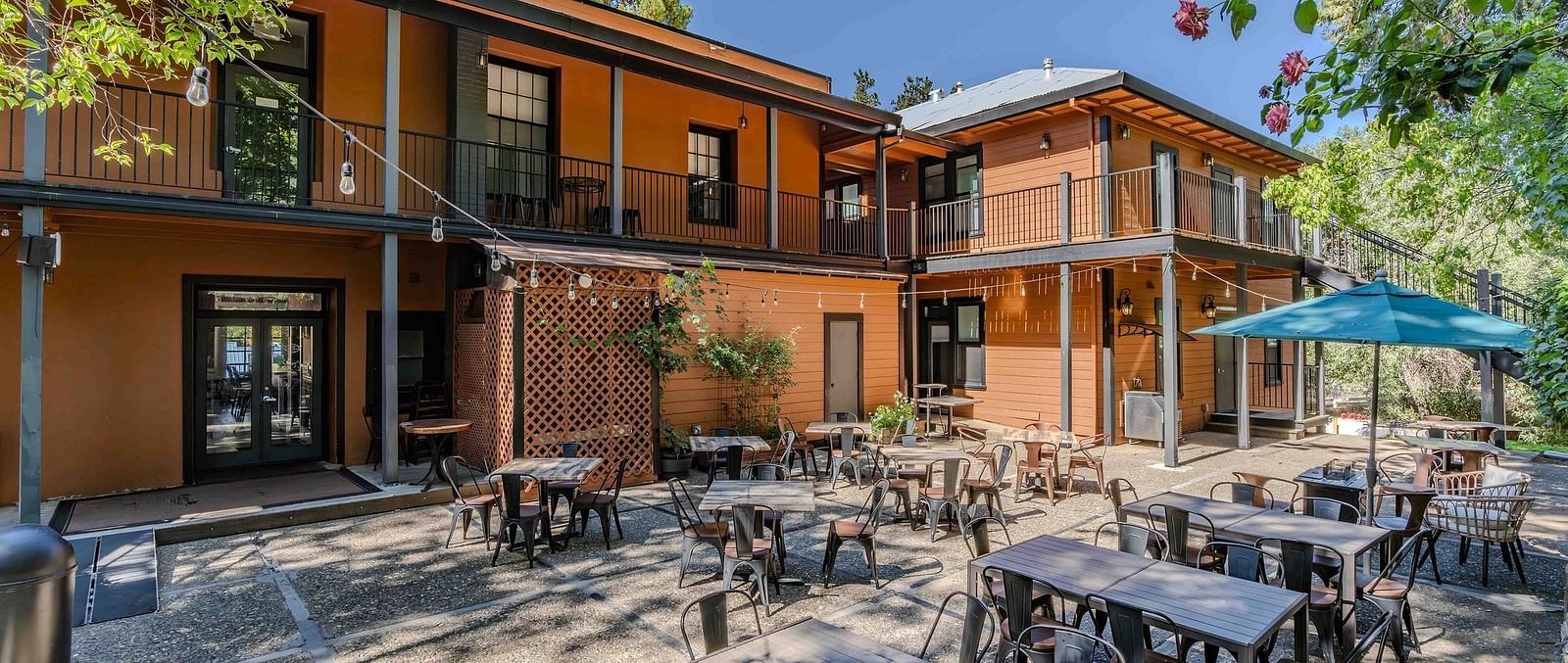 Exterior of The Groveland Hotel with a backyard with outdoor dining.