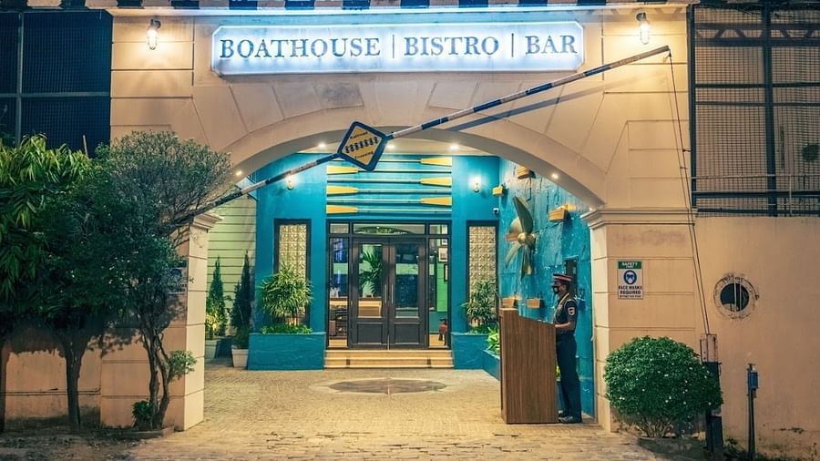 Nighttime view of the entrance to the Boathouse Bistro & Bar, with a sign above the door and a security guard standing by.