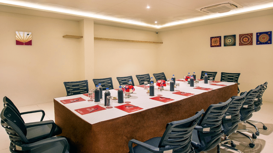 Professional conference room in Lords Inn Jamnagar with organised seating, meeting materials on the table, air conditioning, and refreshments including water bottles and glasses