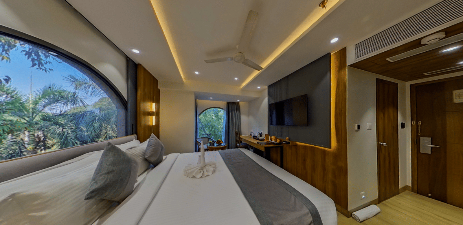 The Standard Room at Lords Inn Vadodara, with a bed placed near a large window, extended wall panelling, and ambient ceiling lights.