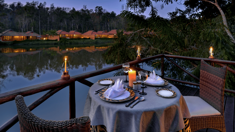 Romantic candlelit riverside dinner setup at night at Evolve Back Coorg