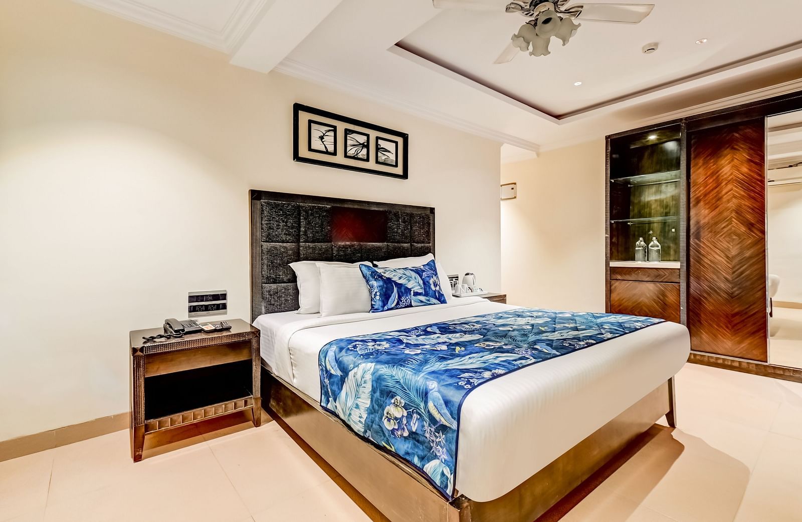 Deluxe room with a private balcony featuring a large bed, flanked by wooden bedside tables, and a photo frame mounted above the headboard