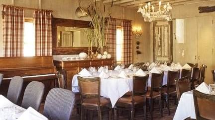 A view of Meeting house private event at Tallman Hotel with meticulously arranged tables and chairs under a chandelier lightning. 