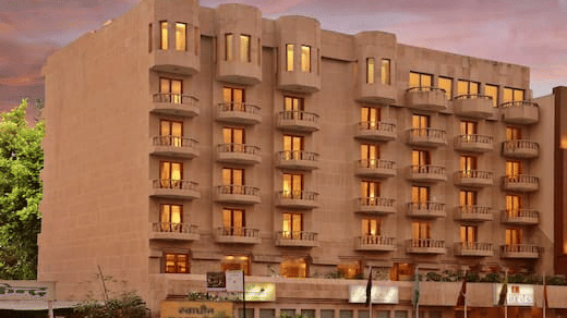 Front view of Lords Plaza Jaipur, building with balconies and warm lighting, set against a pinkish evening sky..