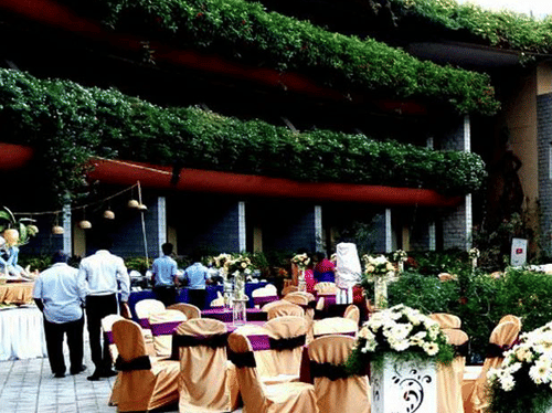 A decorated outdoor event space at Uday Suites features a pool, stage, dining tables, and floral arrangements
