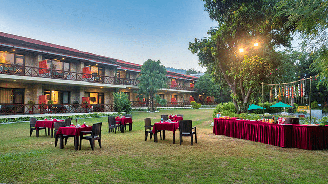 Resort exterior with outdoor dining tables and well-lit pathways at dusk.