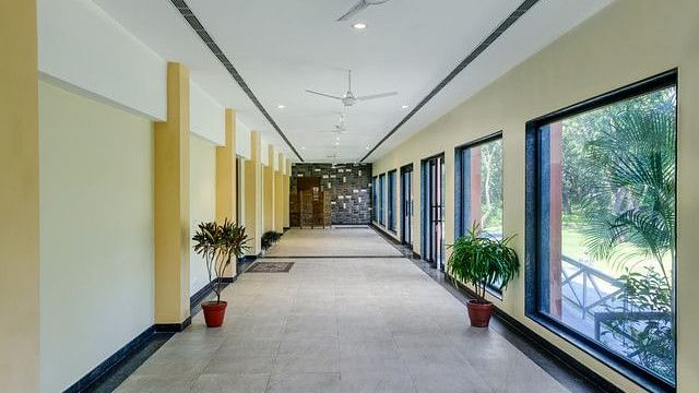alt-text Long hallway with large windows and plants leading to event spaces.