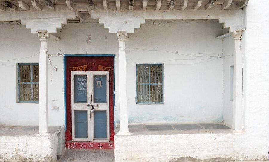 Traditional Anegundi house with white pillars and blue door.