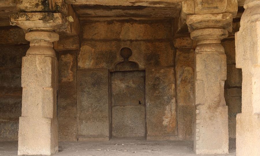 Inscription on a mosque wall with pillars and a doorway.