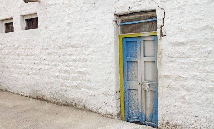 White wall with a weathered blue and yellow door.