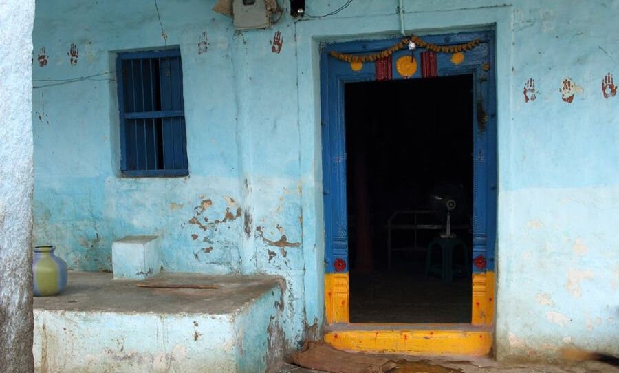 Blue house in Anegundi with painted handprints.