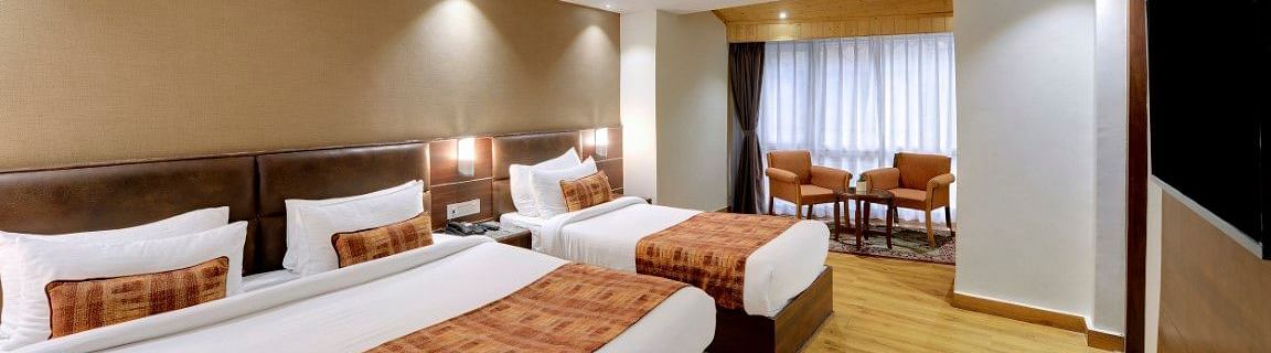 An image of a room with a queen size bed and a single bed with TV and minimal decoration - Sumitel Vista TV Tower