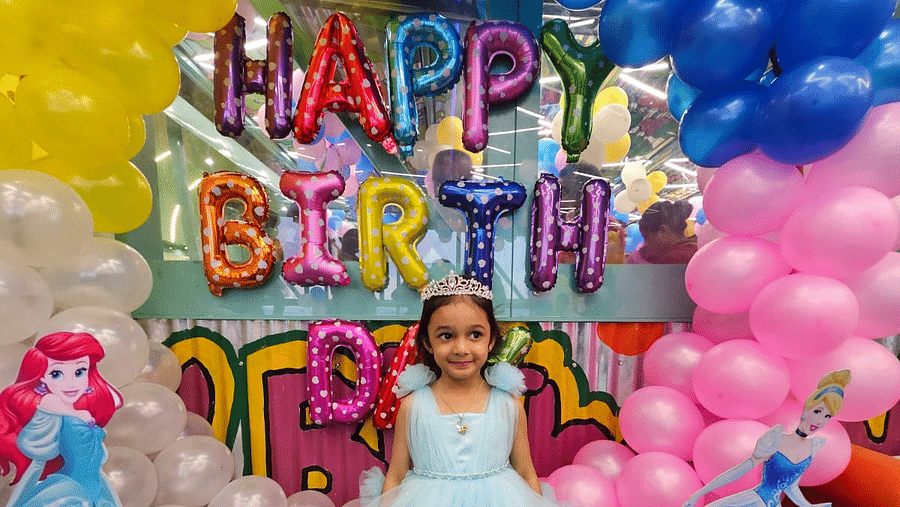 A child in a princess dress standing in front of a vibrant birthday backdrop at Central Courtyard Hotel.