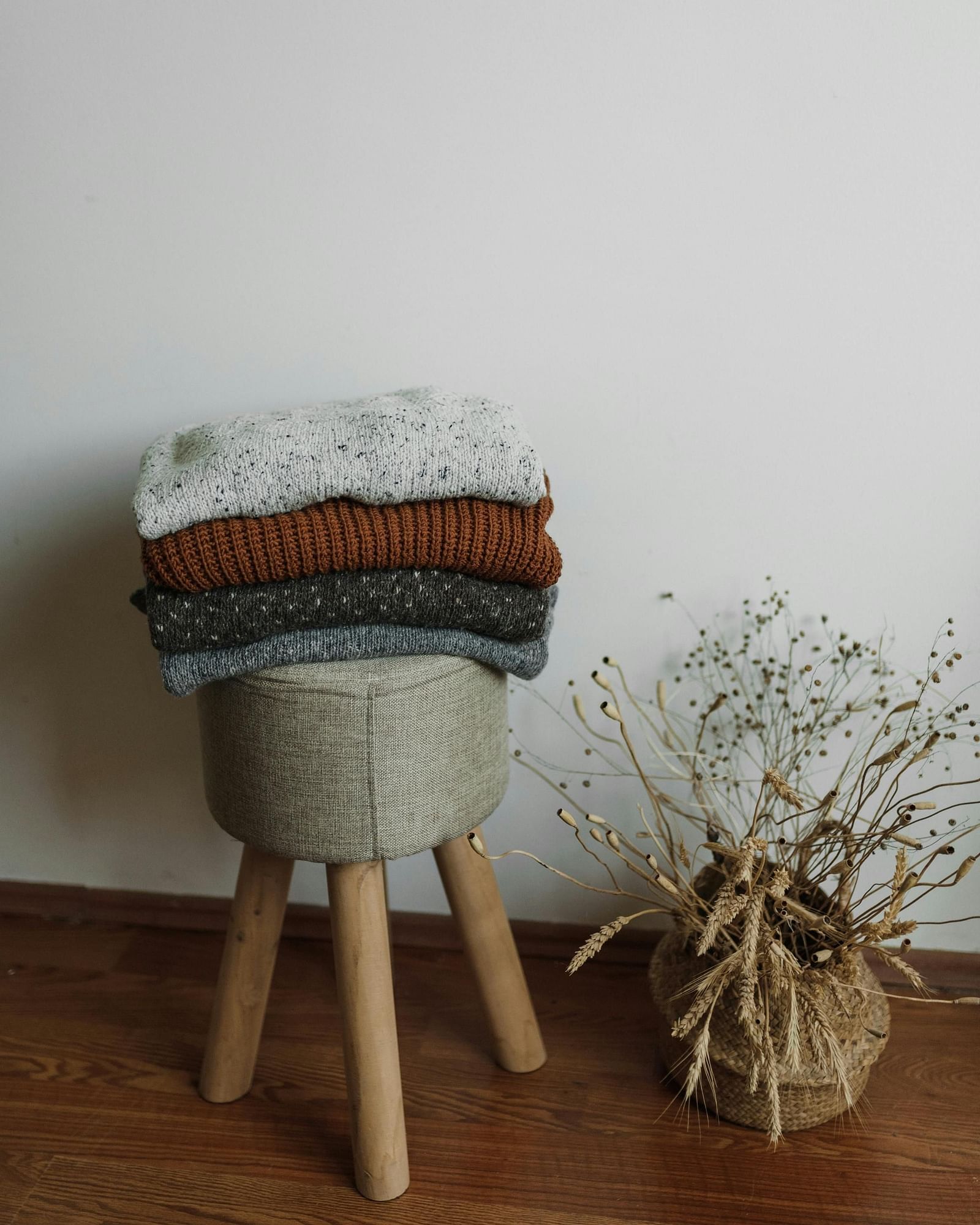 image featuring a few clothes well folded and kept on a cushioned stool 