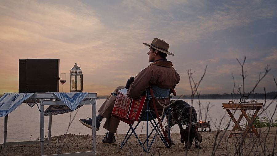 image of a man relaxing and enjoying the mesmerising sunset with a serene lake in front of him at dev shree, deogarh