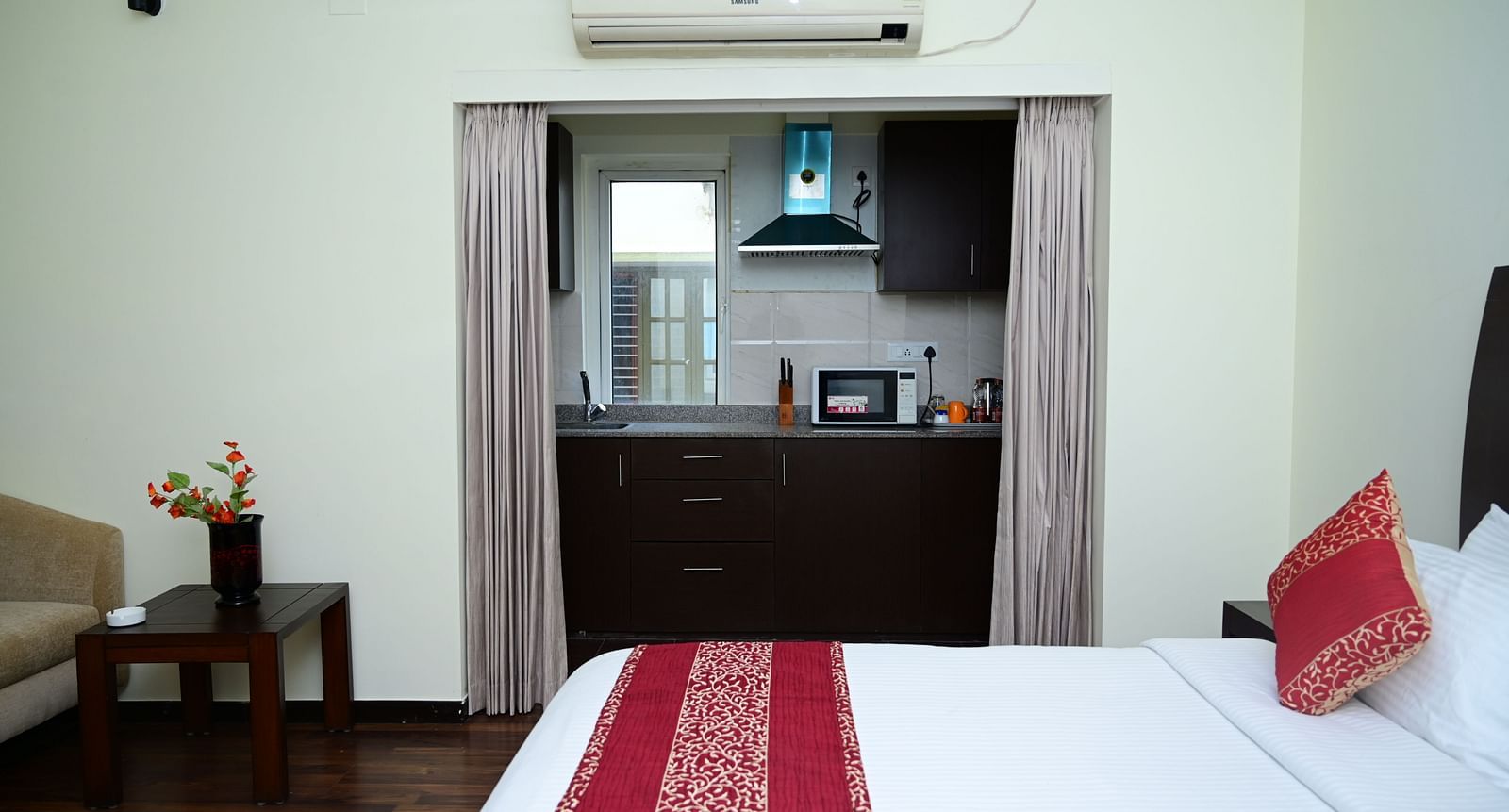 Image of a double bed with pink bedsheet and a kitchen visible from the Executive Suite at Sterling Keys by TGI