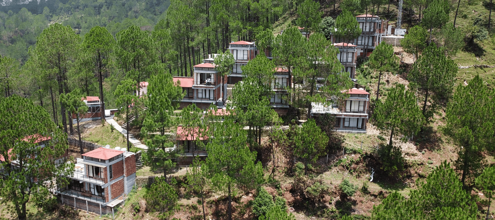aerial view of the BluSalzz Escapade Resort, Lansdowne surrounded by green trees.