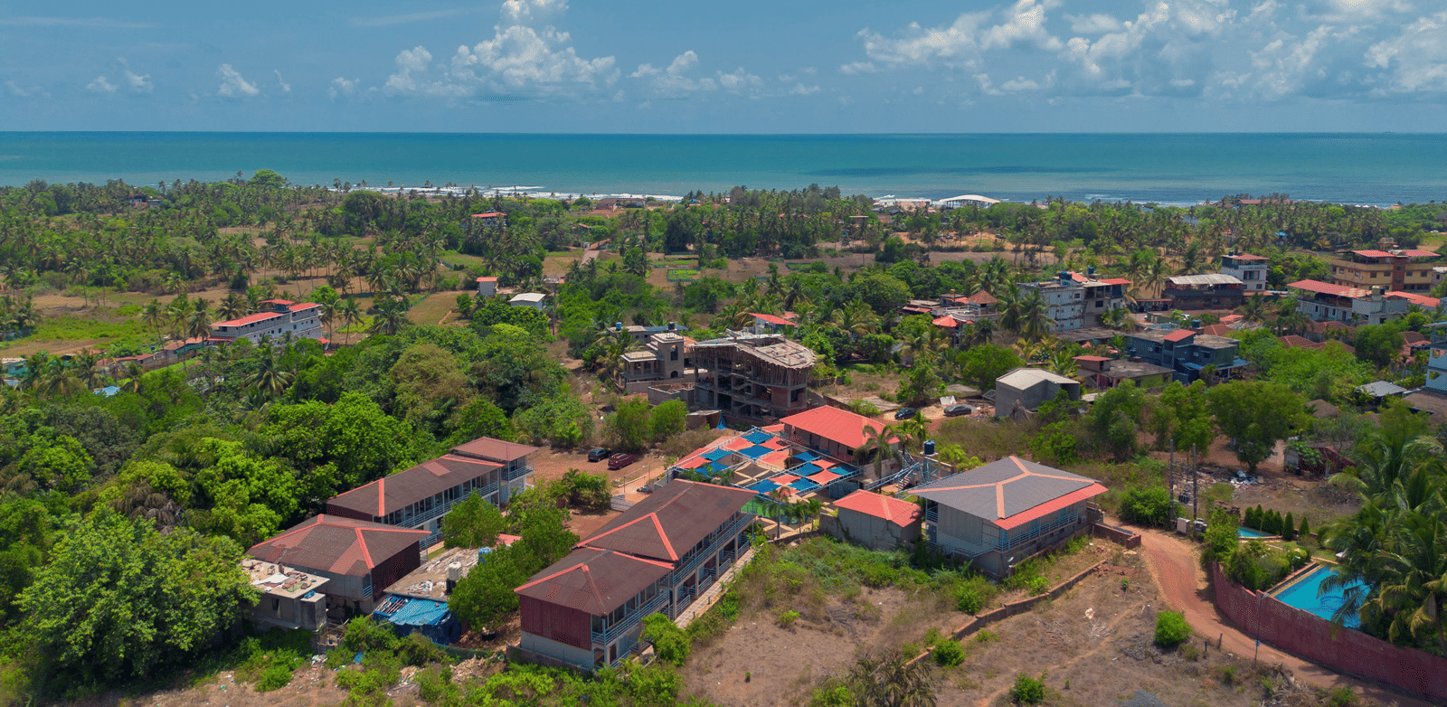 An aerial view of our resort, surrounded by lush green trees with Morjim Beach visible at the edge - Perfectstayz Koko Maya