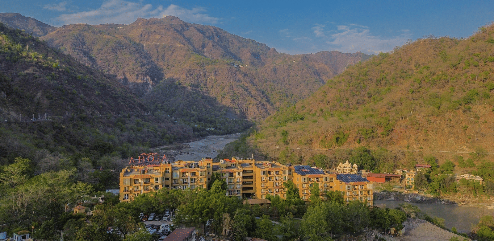 A scenic view of Perfectstayz Value Alpine Retreat, Rishikesh nestled among lush green hills.