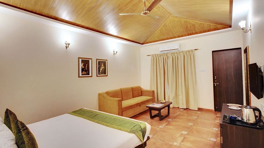 A double bed with sofa and TV in Majesty room at Rahi Forest View