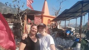 Two people posing for a photo on a street with buildings behind them.