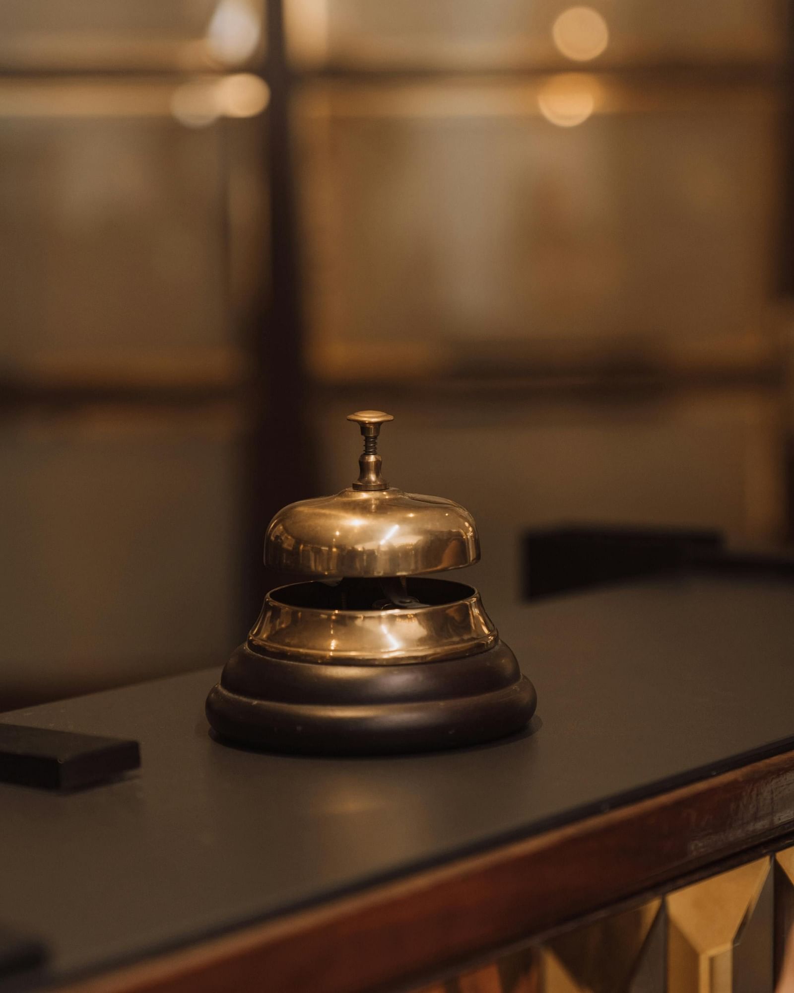 A brass hotel service bell sits on a dark countertop.