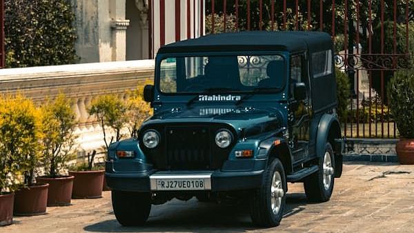A parked Mahindra Thar with potted plants are placed near the walls as decoration during daytime