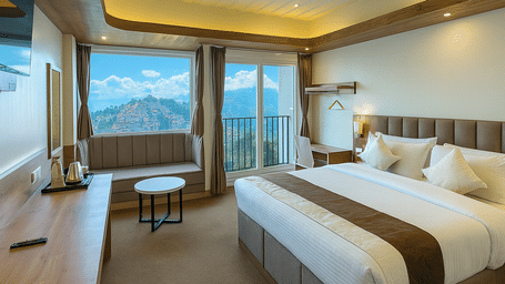 A well-appointed bedroom with a large bed, seating area, and wide windows overlooking mountain view at Avianna Group Of Hotels & Resorts.