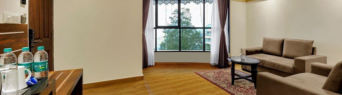 An image of Sumitel Queensyard premium room with sofa sets, ceiling fan and room amenities