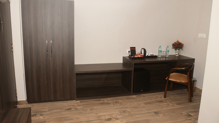 A simple room contains a double bed, a dark wardrobe, a desk, and a chair - Kankidham Lords Inn