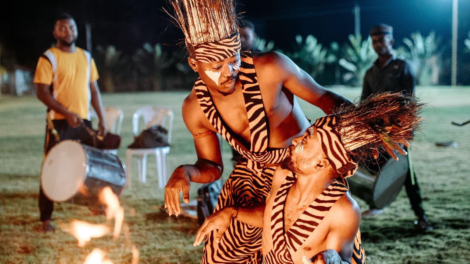 Two people wearing traditional tiger-print outfits and performing while by standers watch -Daksh Eden Greenz, Sasan Gir