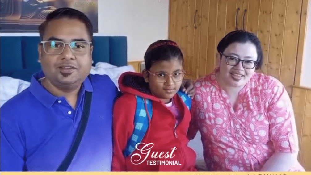 A smiling family of three seated indoors at Avianna Group of Hotels & Resorts, with hotel branding  Luxury That Connects Service -That Cares at the top and contact information, website, and location tags displayed at the bottom. 