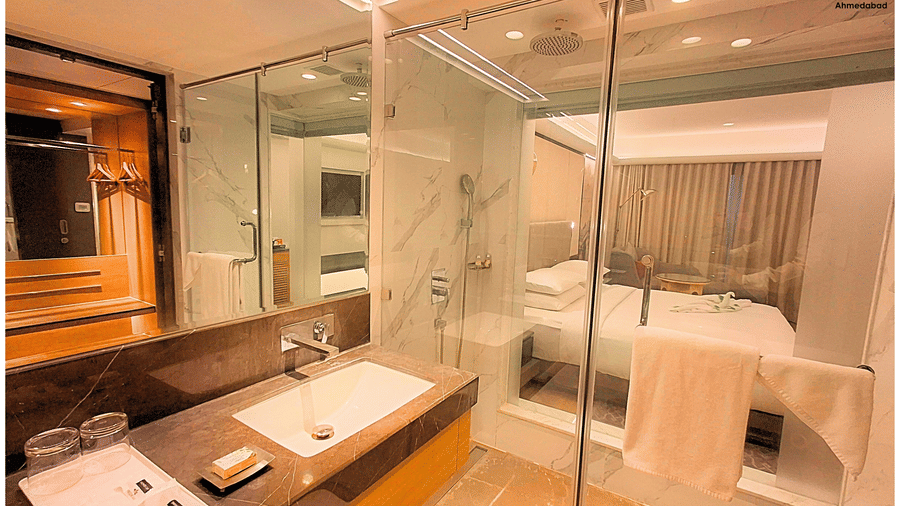 Deluxe King Room at Pride Plaza Ahmedabad offering a contemporary glass enclosed shower area, marble finishes, sleek fittings and well lit bathroom space for enhanced comfort.