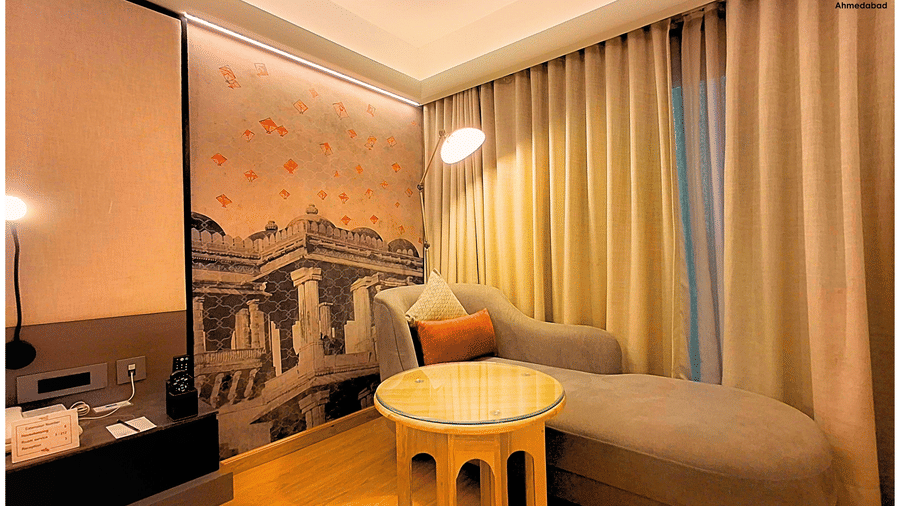 Deluxe King Room at Pride Plaza Ahmedabad presenting a cosy lounge corner with upholstered seating, soft lighting, wooden accents and spacious layout ideal for unwinding after a long day.