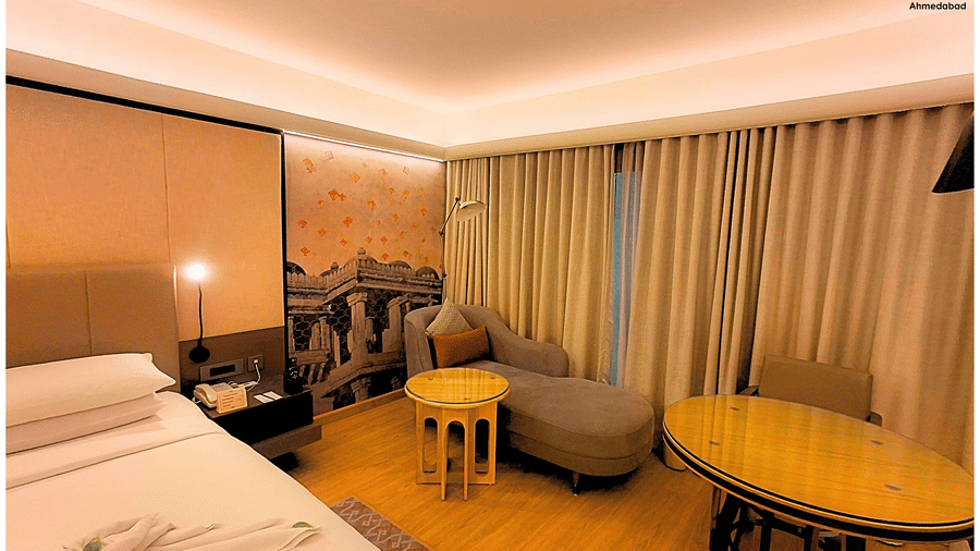 Deluxe King Room at Pride Plaza Ahmedabad highlighting a comfortable seating area with round table, elegant curtains, warm lighting and thoughtfully designed interiors for a relaxing stay.