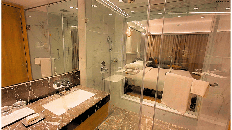 Superior King Room at Pride Plaza Ahmedabad offering a well appointed marble bathroom with glass shower enclosure, modern sanitary fittings, glass door and neatly arranged bath amenities.