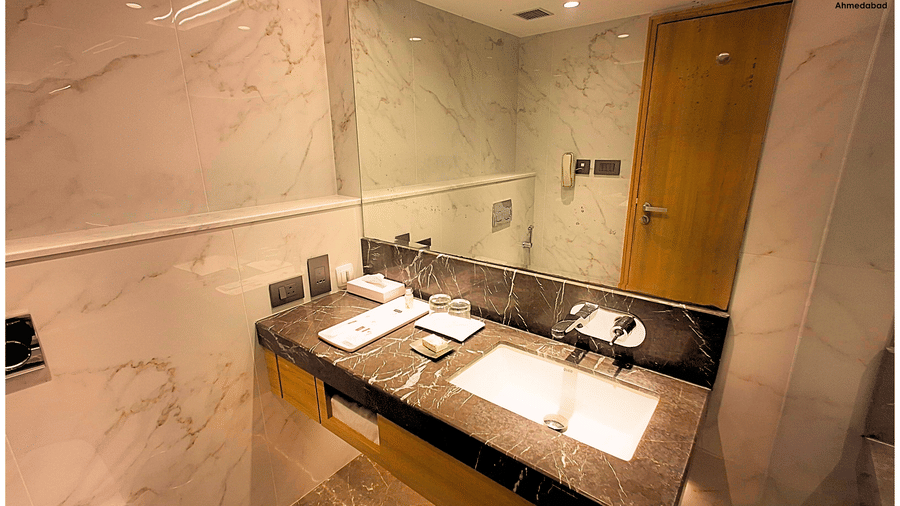 Superior King Room at Pride Plaza Ahmedabad featuring a marble bathroom vanity with large mirror, premium fittings, spacious counter and modern lighting for added convenience.