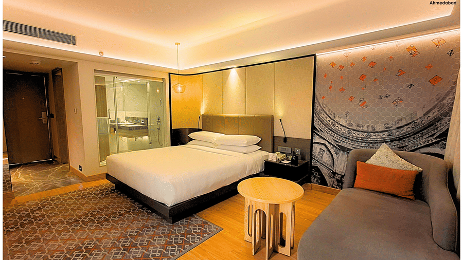Superior King Room at Pride Plaza Ahmedabad displaying a spacious king size bed, contemporary wall art, plush seating, wooden flooring and soft ambient lighting for a refined stay.