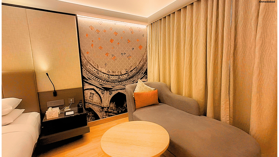 Superior King Room at Pride Plaza Ahmedabad highlighting a well designed lounge area with upholstered seating, round table, warm tones and spacious layout suited for relaxation.