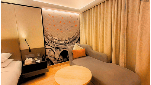 Superior King Room at Pride Plaza Ahmedabad highlighting a well designed lounge area with upholstered seating, round table, warm tones and spacious layout suited for relaxation.