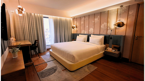 Spacious Bedroom with Modern Furniture and Artwork in Royal Suite at Pride Plaza Ahmedabad.