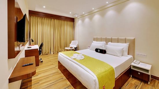 Deluxe Room With Breakfast is host to King Size bed with bedside tables, a sitting chair, warm overhead lighting, work desk and wall-mounted TV.