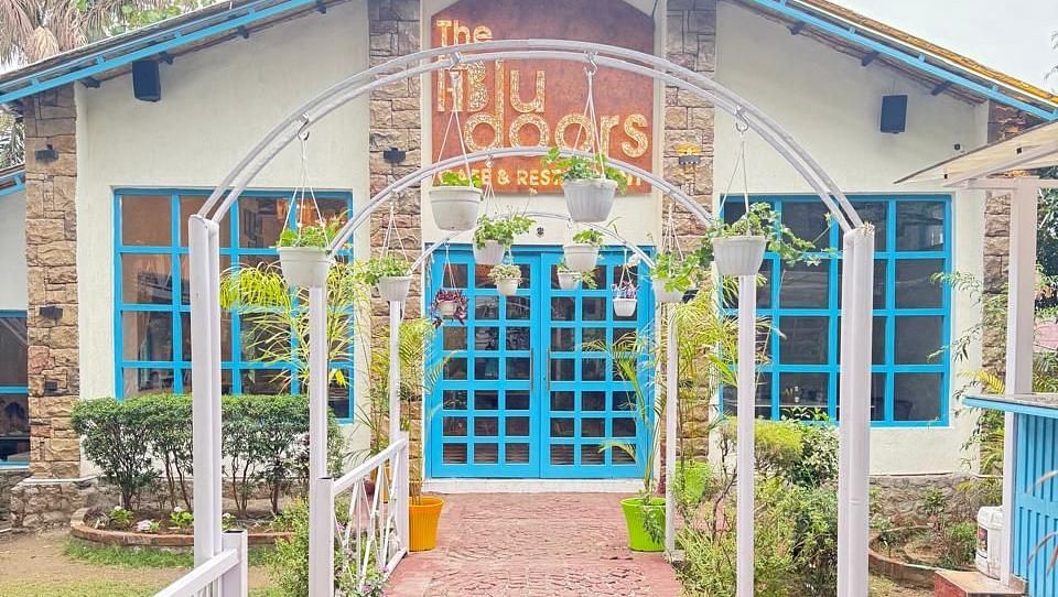 Exterior view of 'The Blu Doors Cafe and Restaurant' with blue doors, arched walkway, and garden.