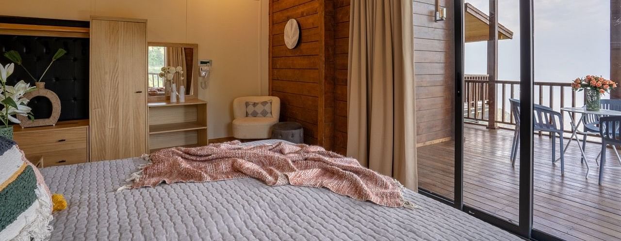 An image of a bedroom with king size bed, frames on the wall, a dressing table, a cabinet at Avalon Cottages, Kanatal