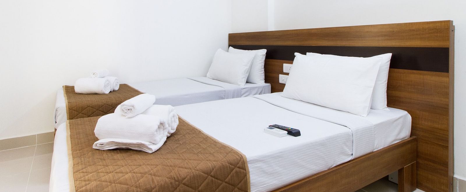 A hotel room offering two single beds both with brown bedding at Sanctum Suites Whitefield, Bangalore.