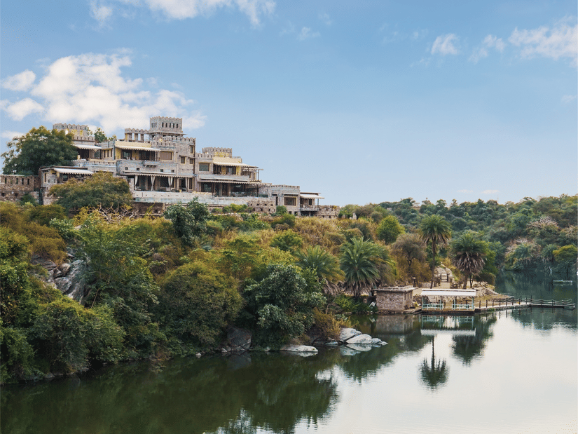 A scenic view of Chunda Shikar Oudi,a lakeside resort surrounded by lush greenery and serene waters under a clear blue sky