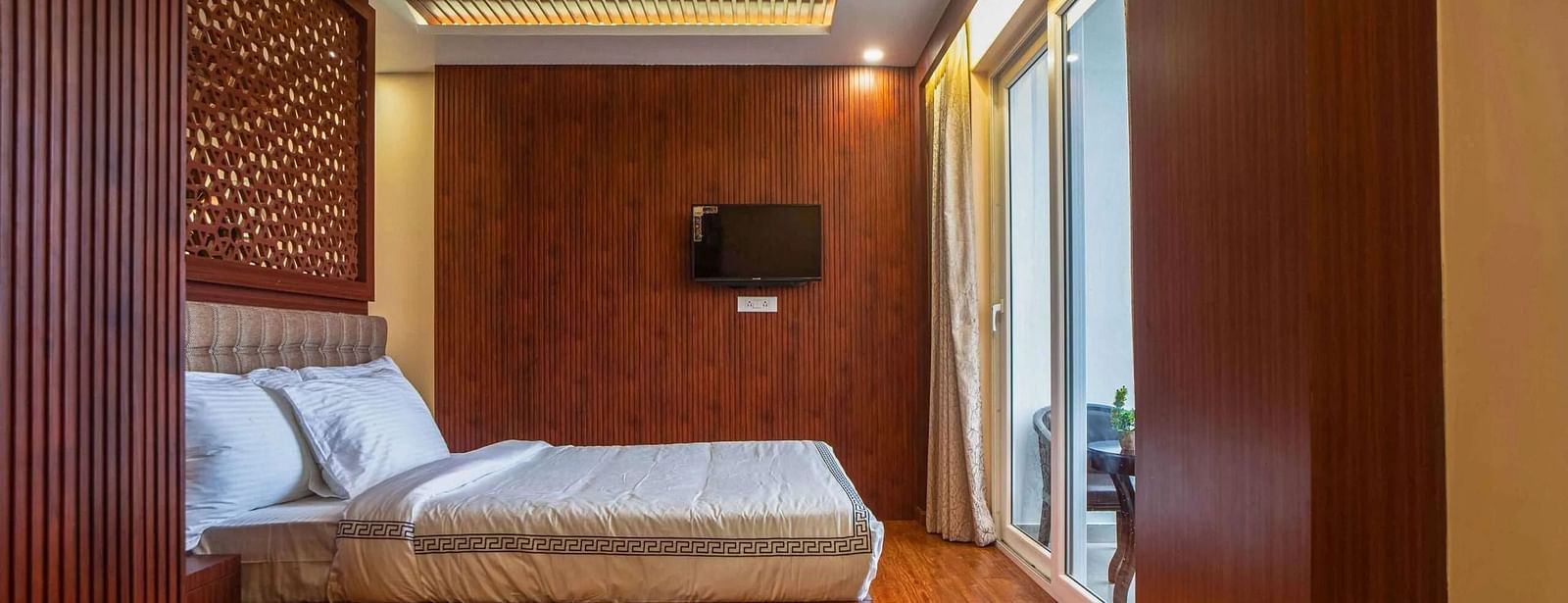 A stylish room at Mansha Palace offers a comfortable bed, a coffee table, a TV, and balcony access.
