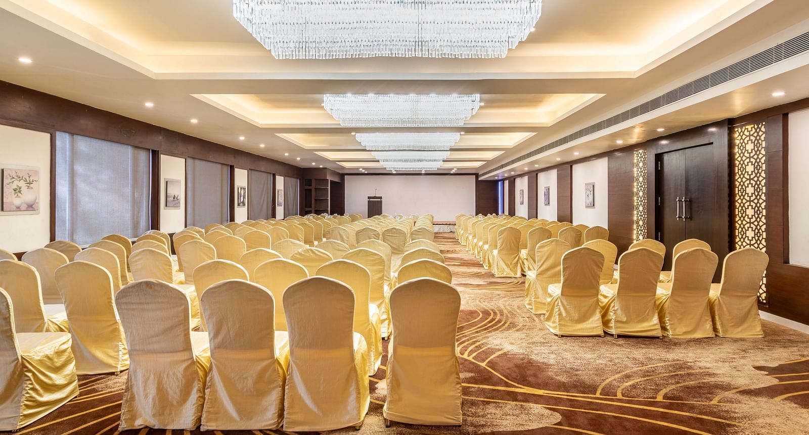 Elegant banquet hall with chandelier lighting and gold-covered chairs arranged for a formal event