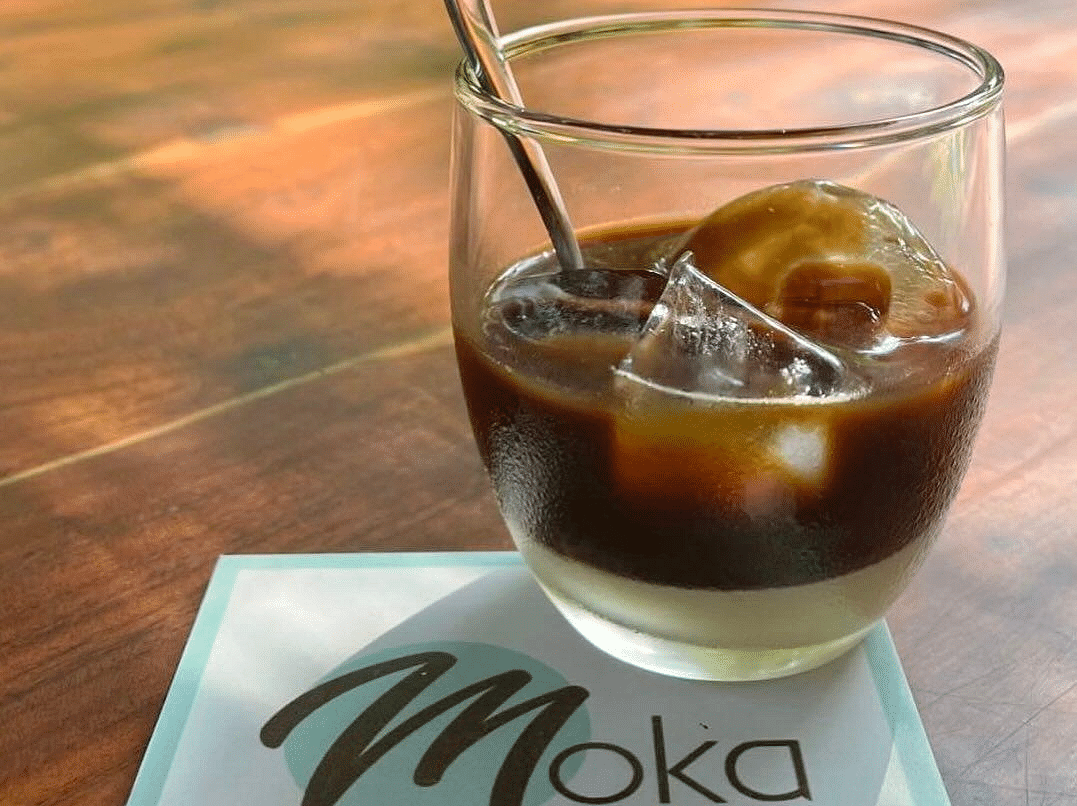 a glass of iced coffee with the coaster of Moka